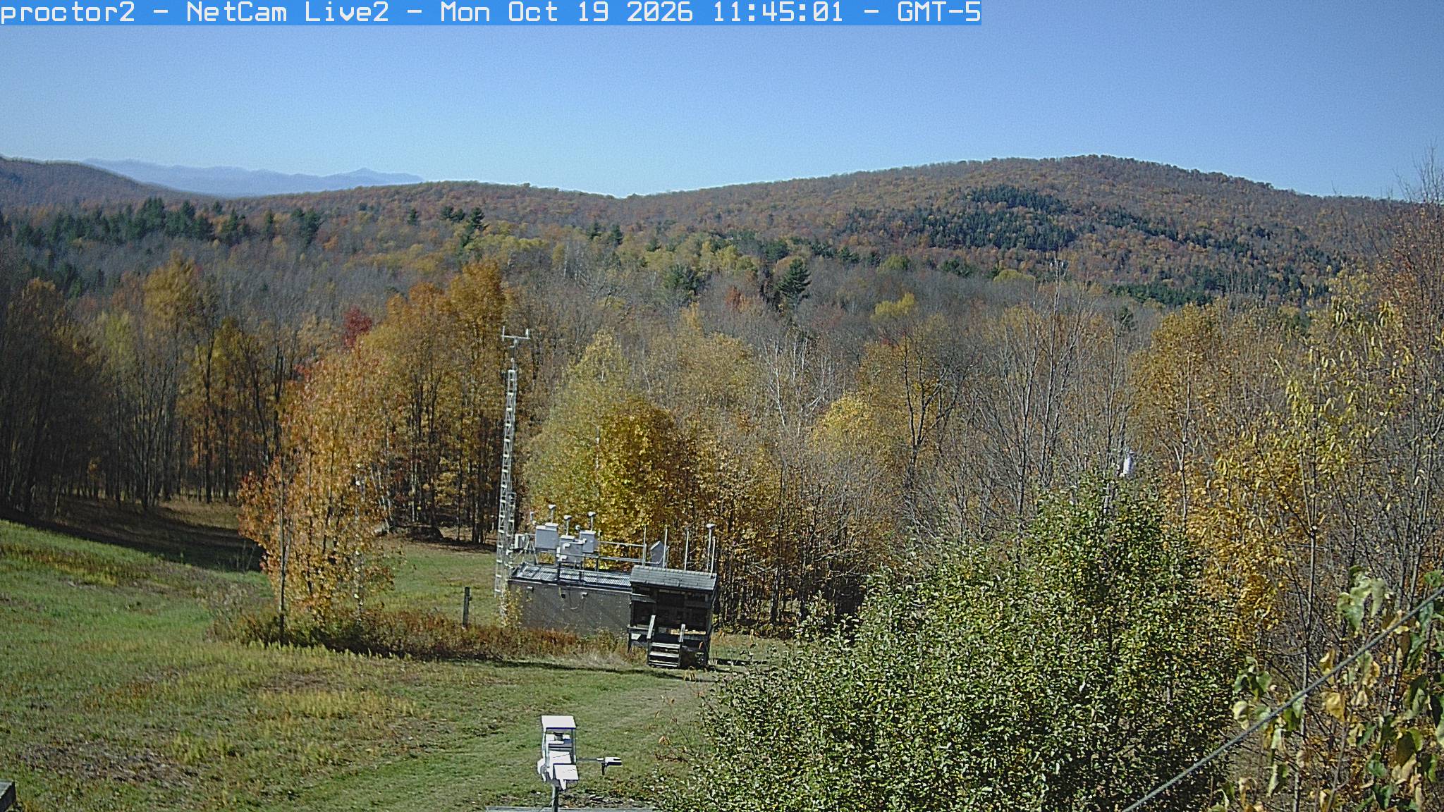 Wooded hills rise beyond an open foreground with research instruments.