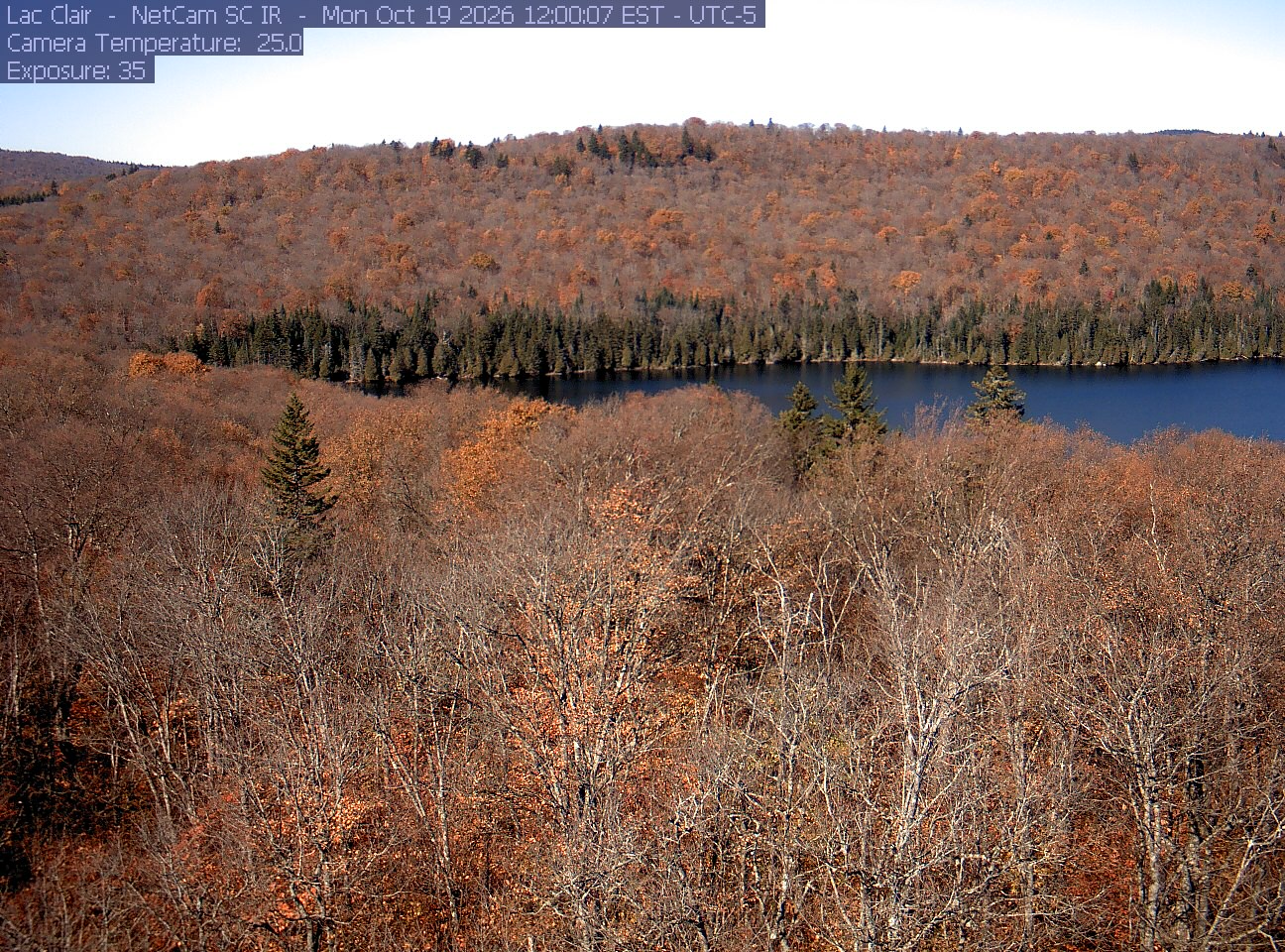 A wooded hillside and close canopy frame the water at Lac Clair.