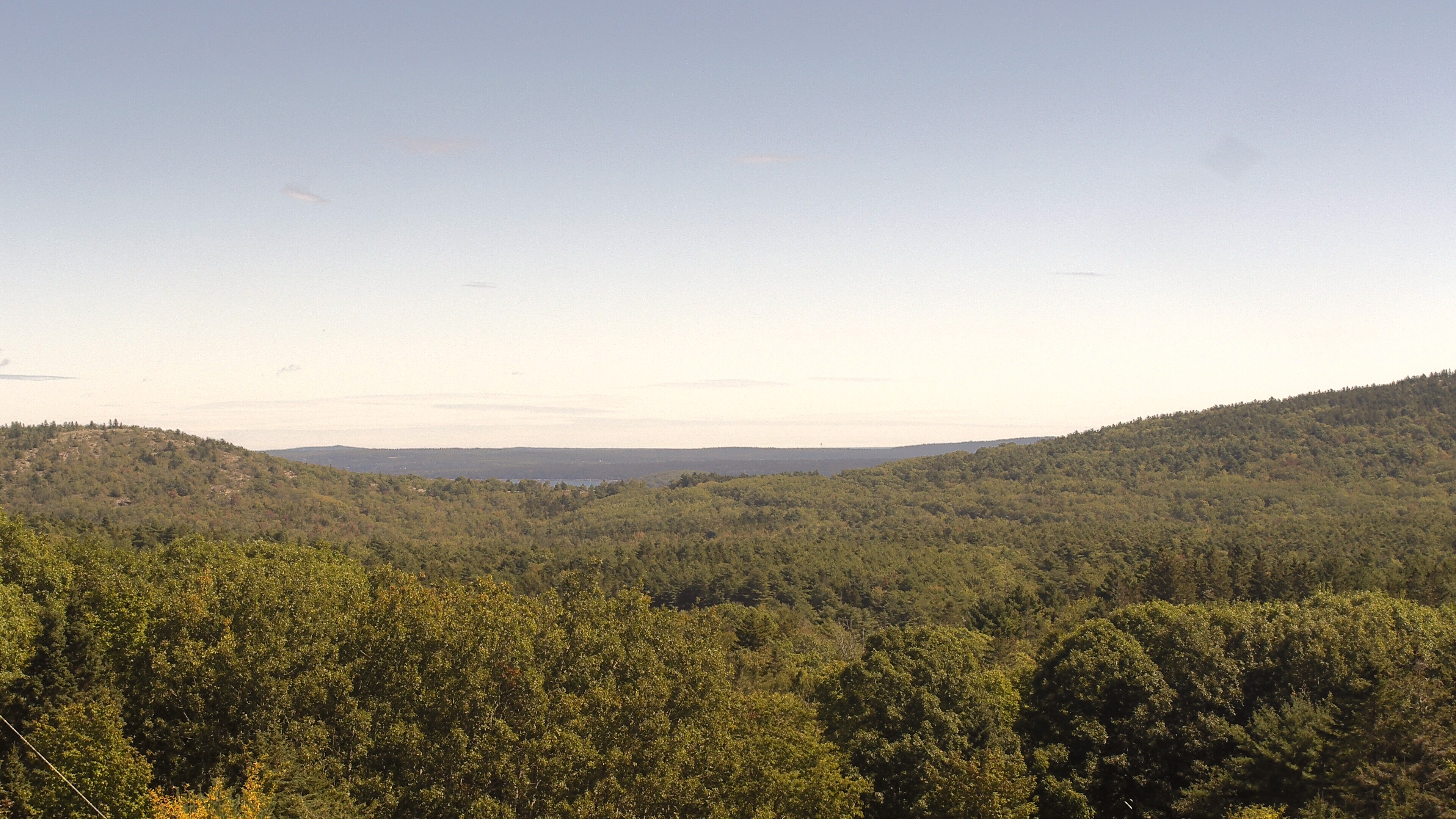 A wooded valley opens toward distant water, seen from McFarland Hill.