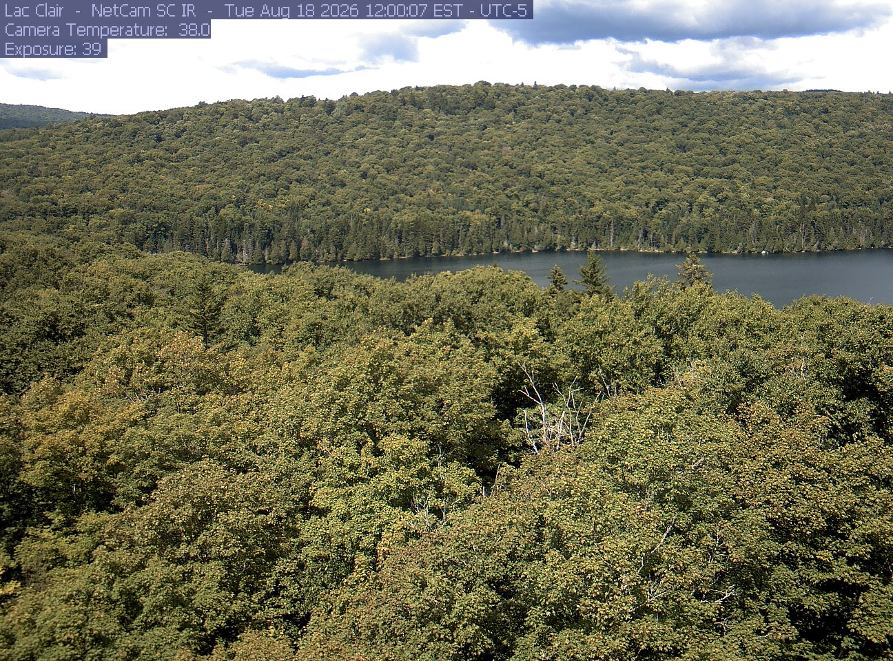 A wooded hillside and close canopy frame the water at Lac Clair.